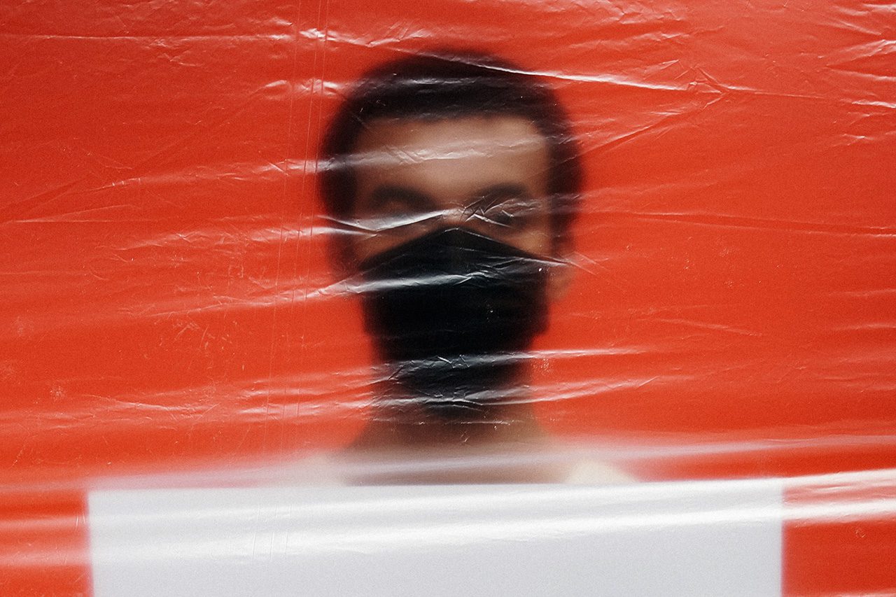 Man in Covid mask behind plastic screen