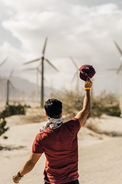 Man waiving hat at windmills