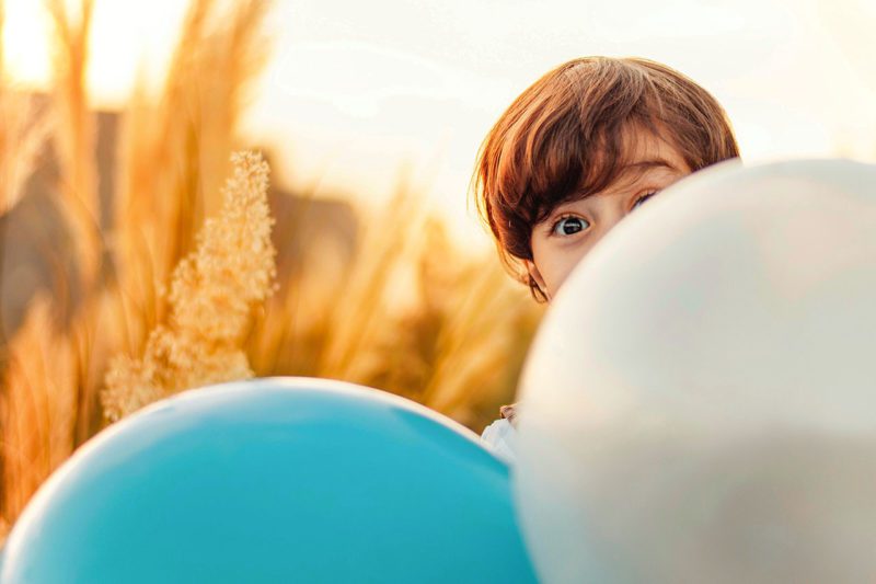 Child hiding behind balloons