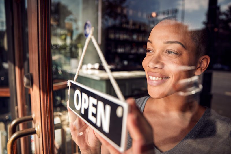Black woman with open store sign