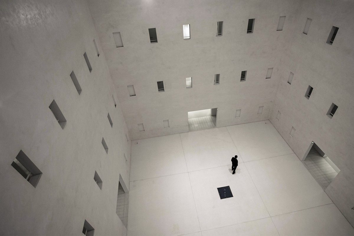 Man in white room with black hole in floor