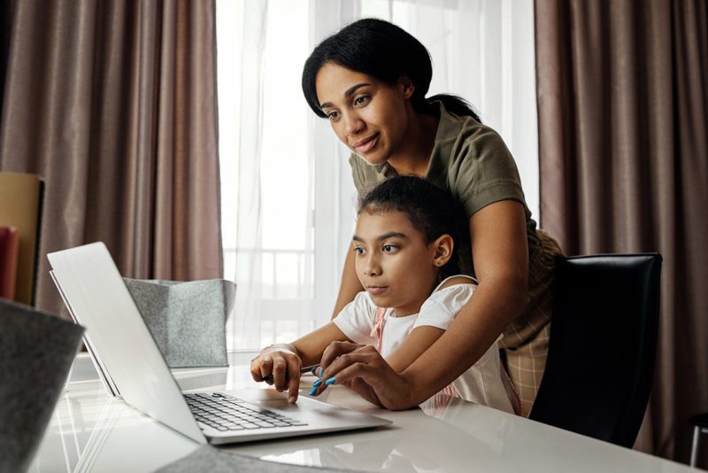 Mother helps child student with work at computer