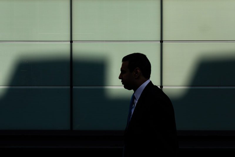 Man in shadows walking in front of panelled wall