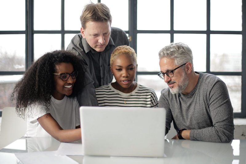 Diverse group of employees around a laptop