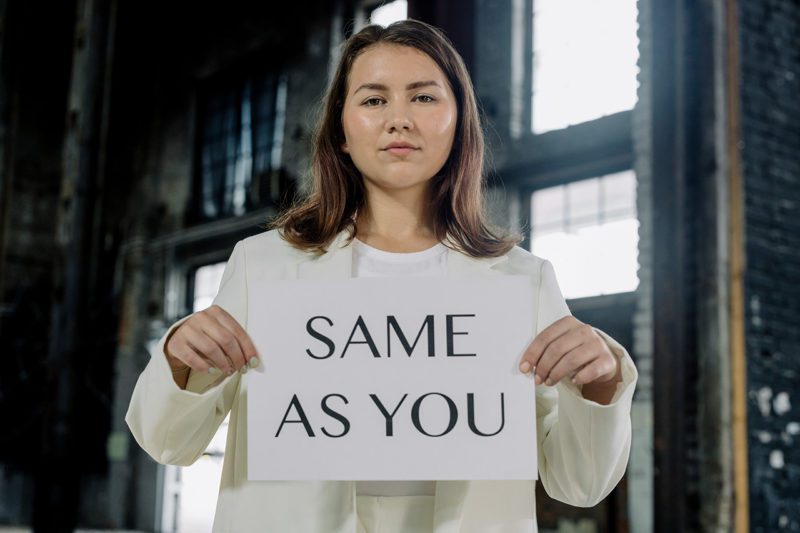 Woman holding Same As You sign