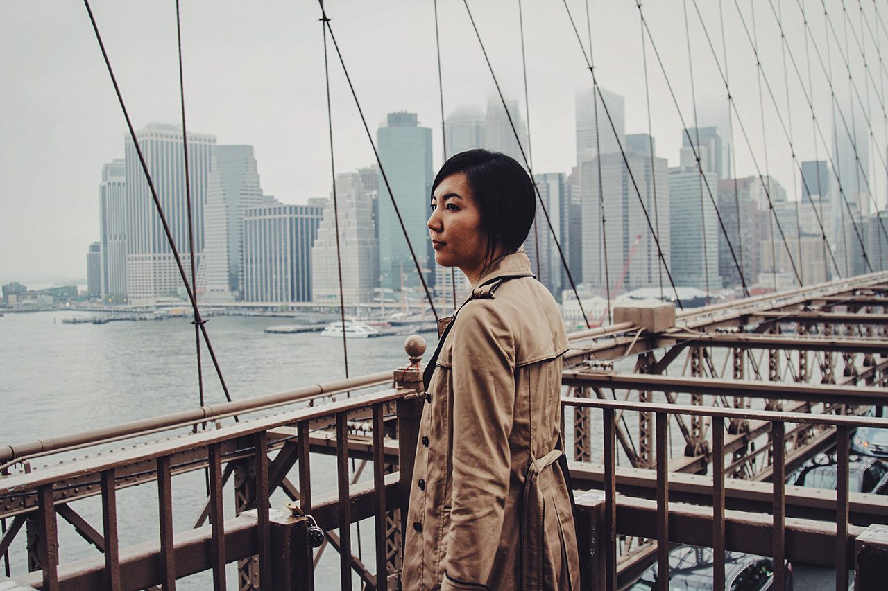 Woman in raincoat on city bridge