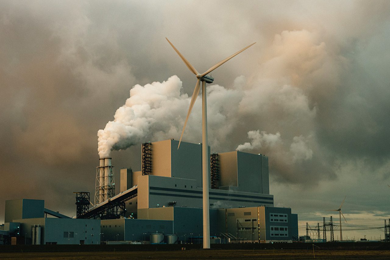 Windmill in front of polluting factory