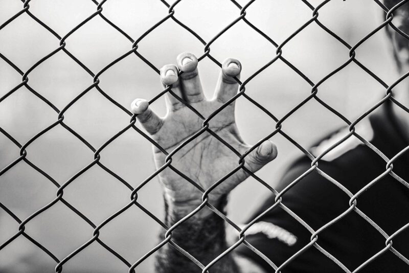 Hand against prison fence