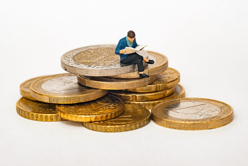 Small person reading on stack of coins