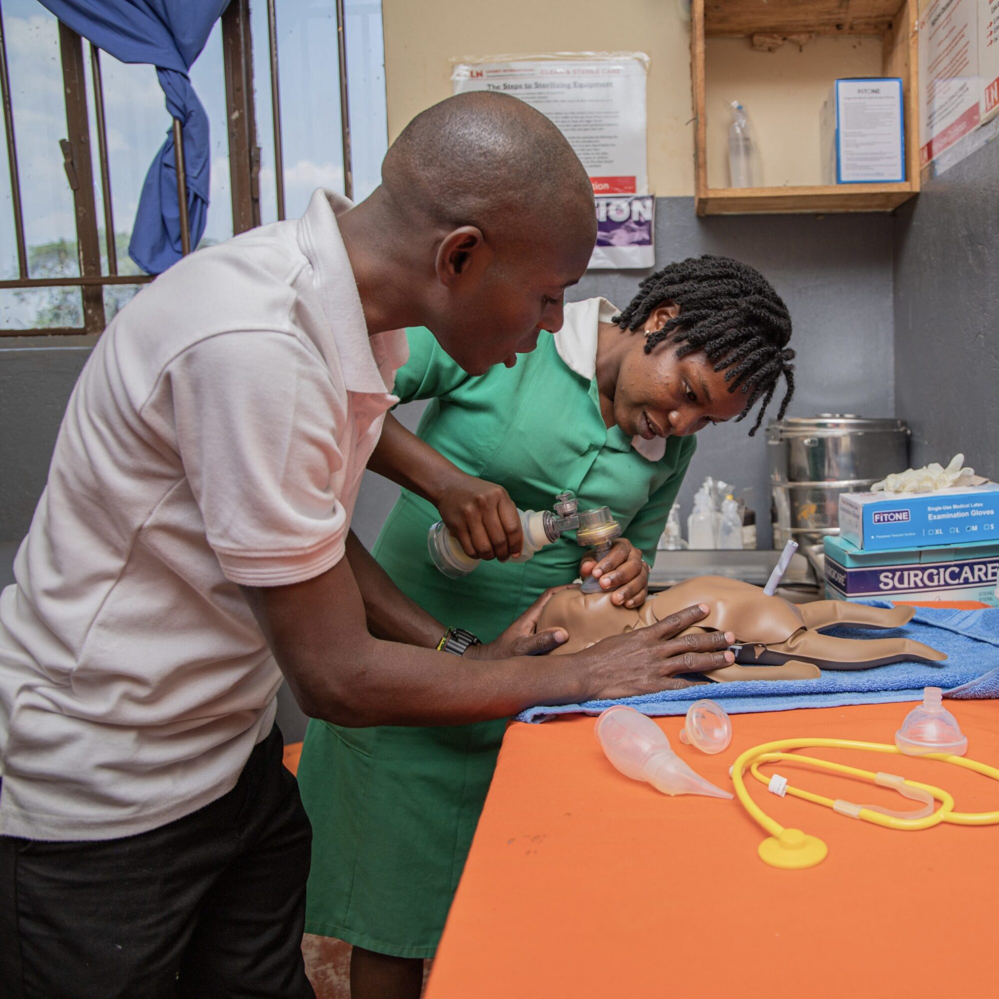 African male and female healthcare workers training on fake baby