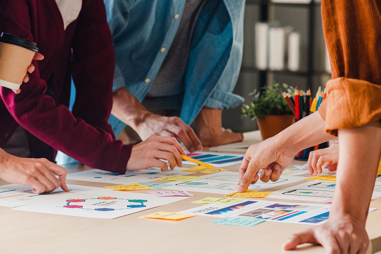 Hands working collaboratively with post its and paper
