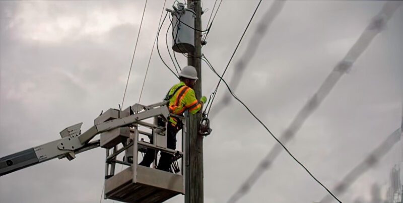 Worker hanging fiber from street pole