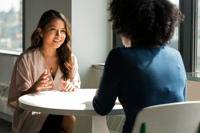 Asian worker speaking to black worker