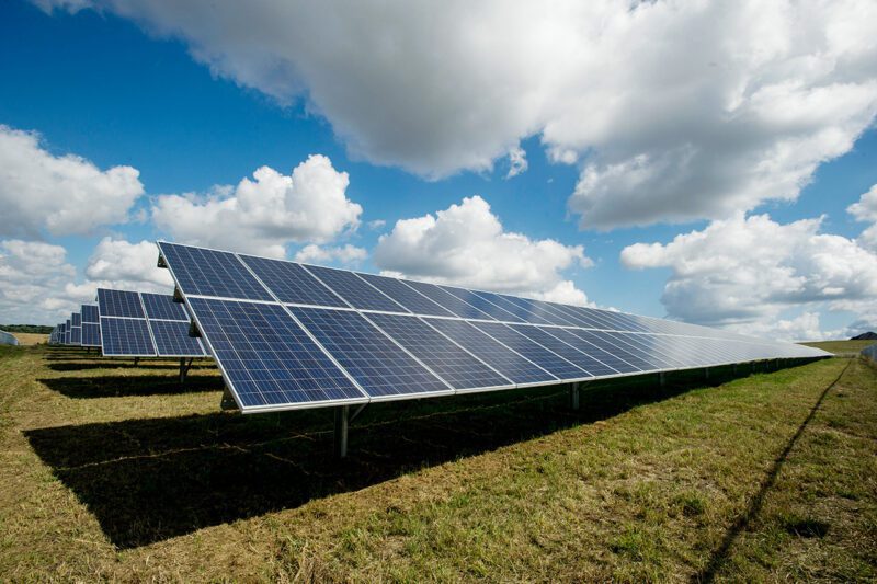 Solar panel in field under clouds and sun