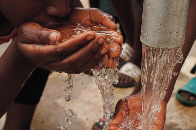Boy drinking water our of cupped hands
