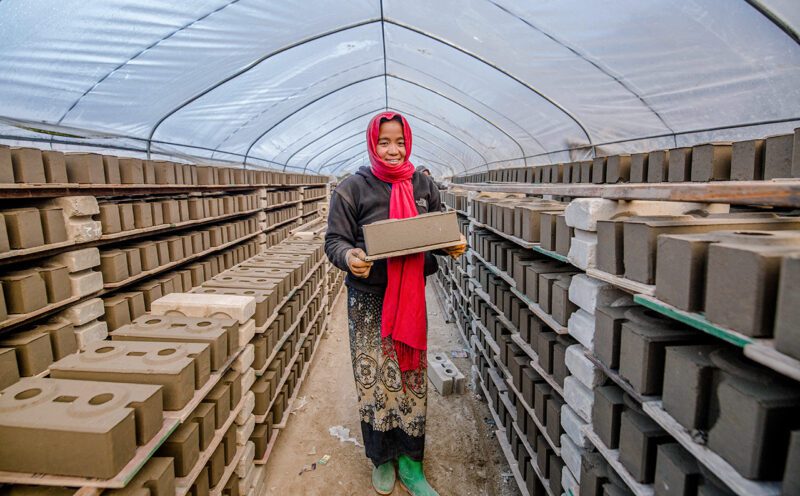 Nepalese woman Stacking cured bricks.