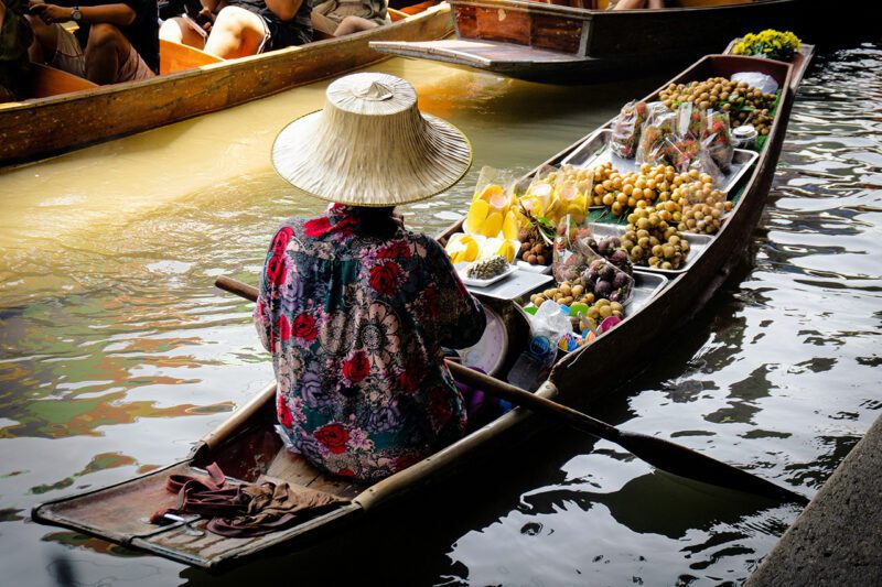 Asian man in boat transporting goods