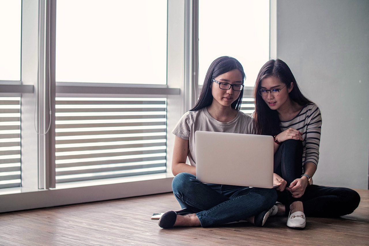 Two Asian women entrepreneurs on laptop on floor