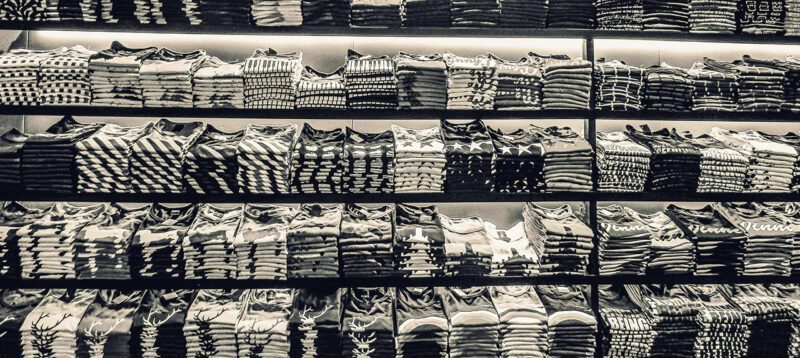 Black and white photo of many piles of fast fashion clothing