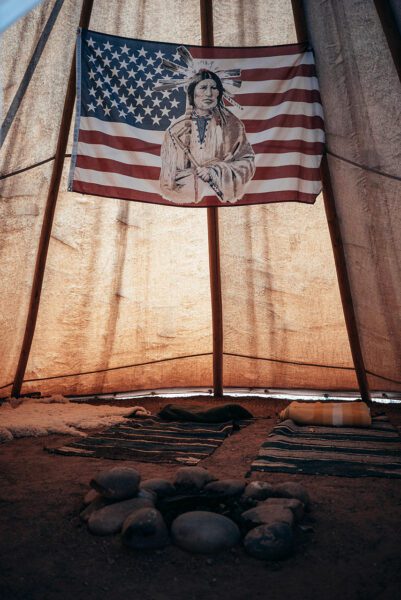 Native American on American Flag in simple abode
