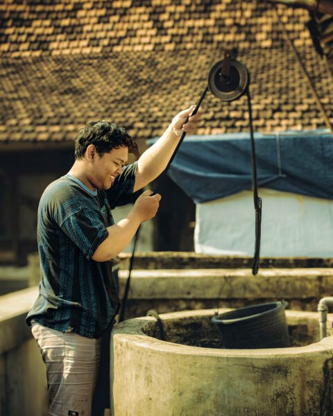 Asian man gathering water at well