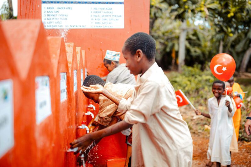 Africans drawing water from orange containers