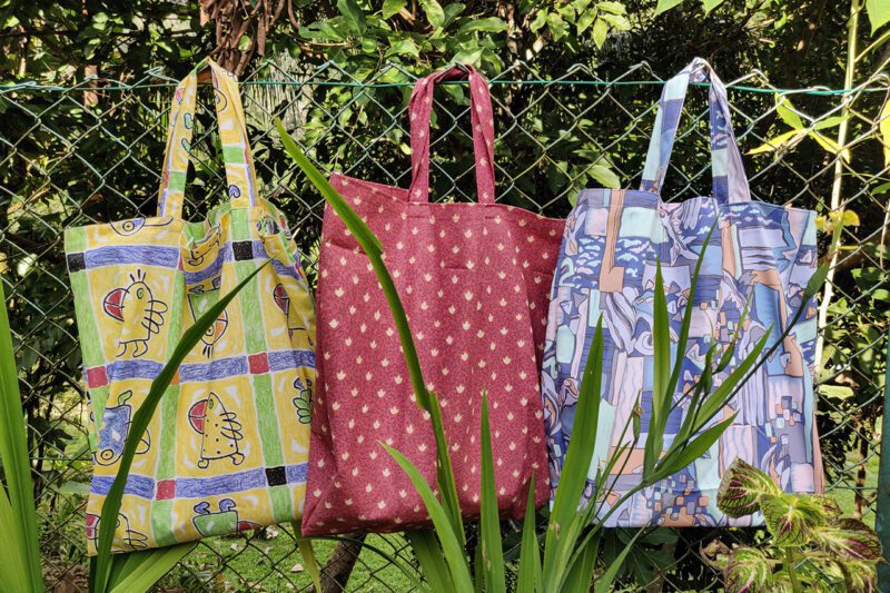 Three handmade bags hanging on fence