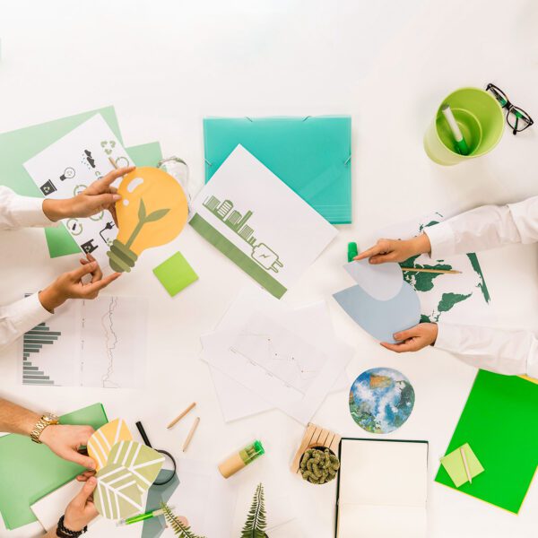 Hands around conference table with papers and cutouts