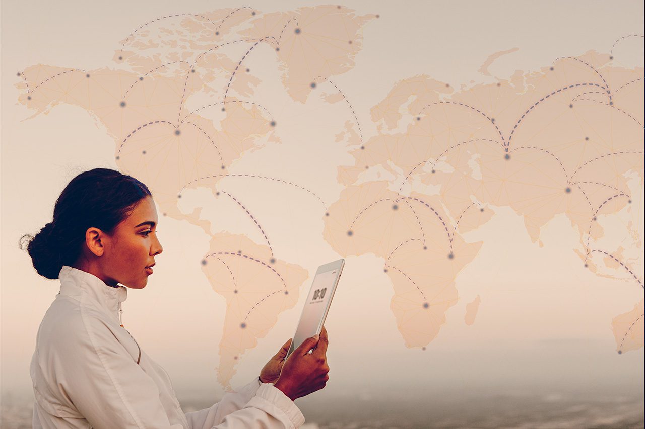 Woman holding tablet in front of world map