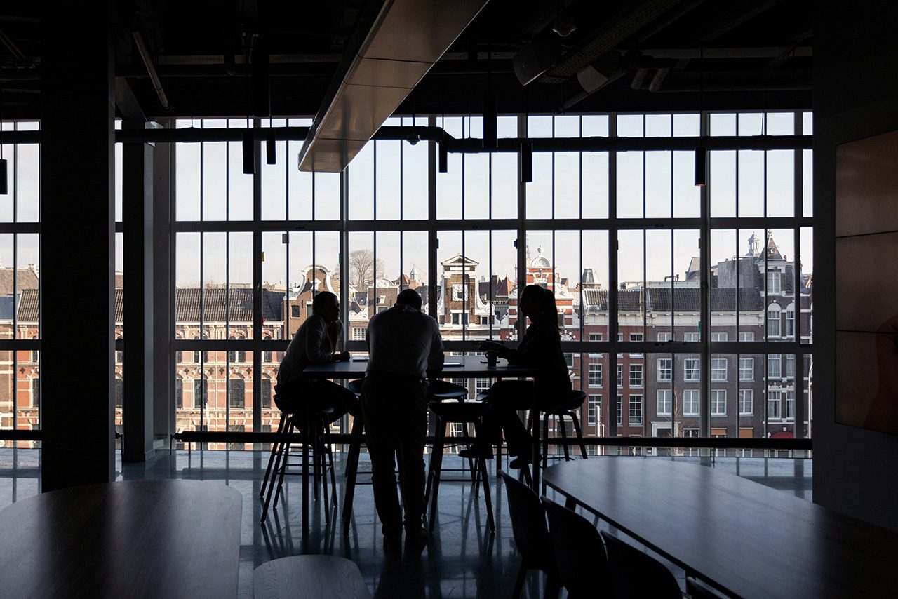 Workers meet in front of large window