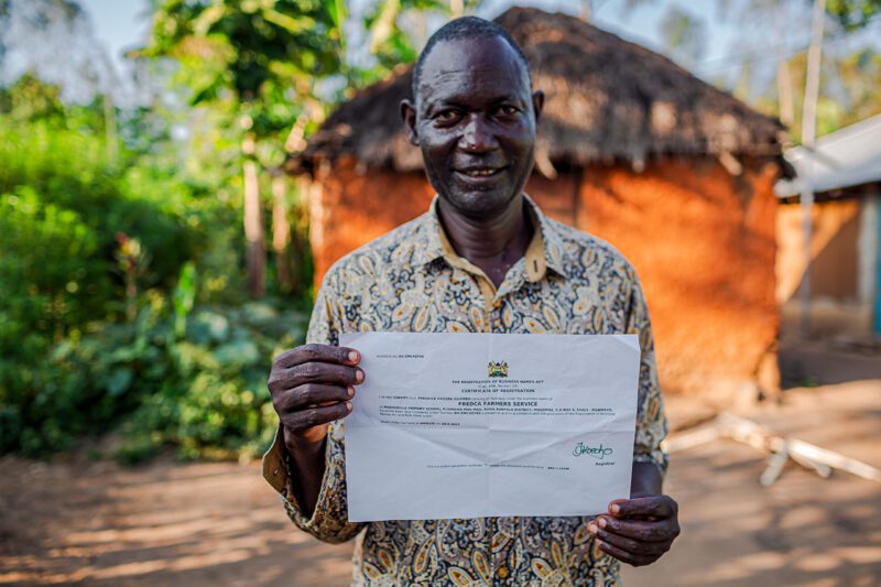 African man holding certificate of registration.