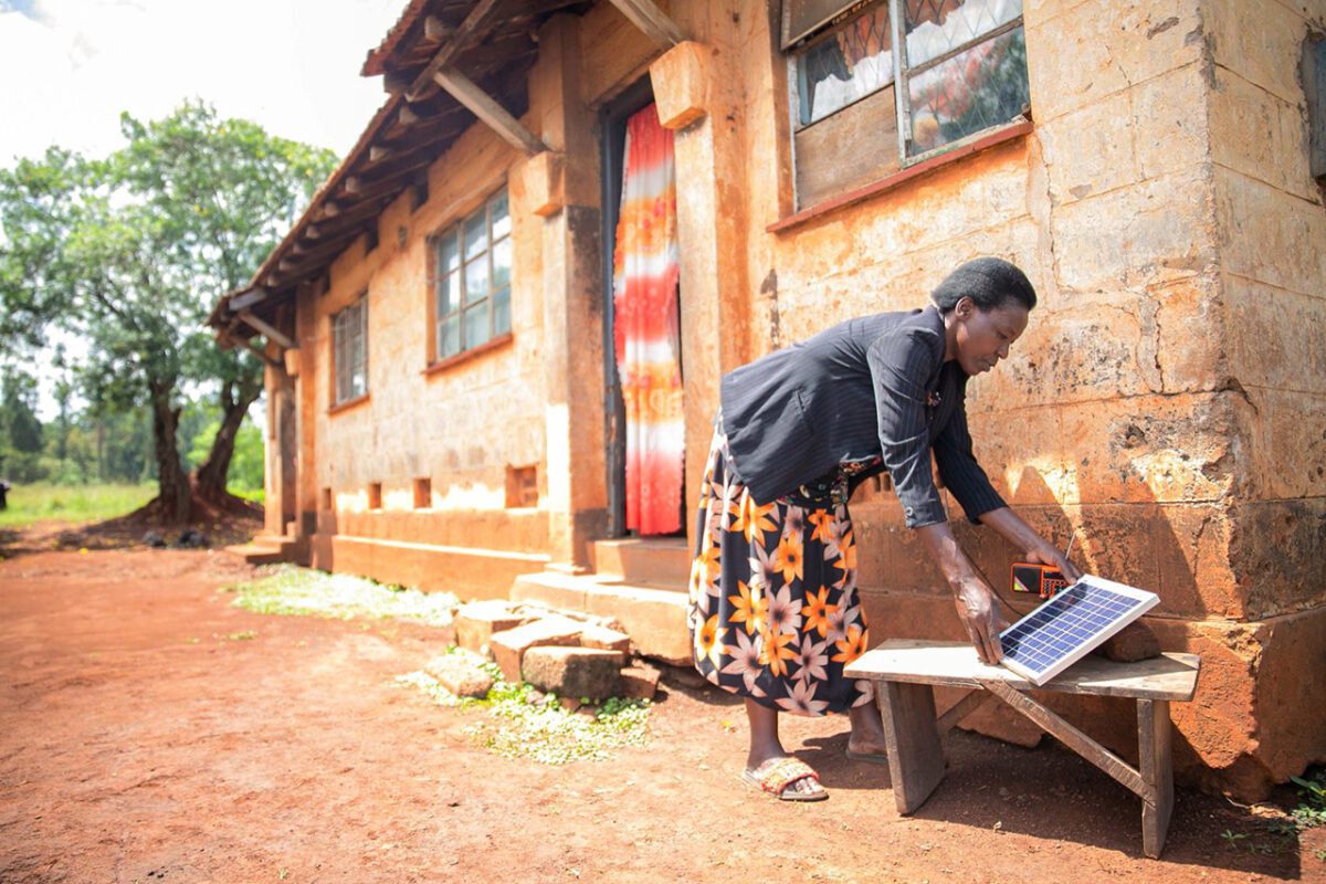 woman holds a solar panel at Masindi District of Western Uganda with the Pay as You Go System - Image Courtesy of New Energy Nexus FEATURED