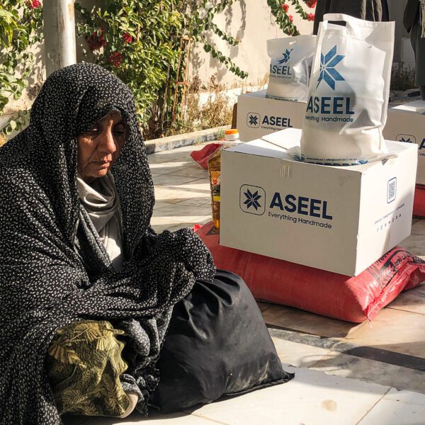 Afghan woman sitting next to boxes