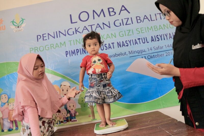 Indonesian child being weighed on scale