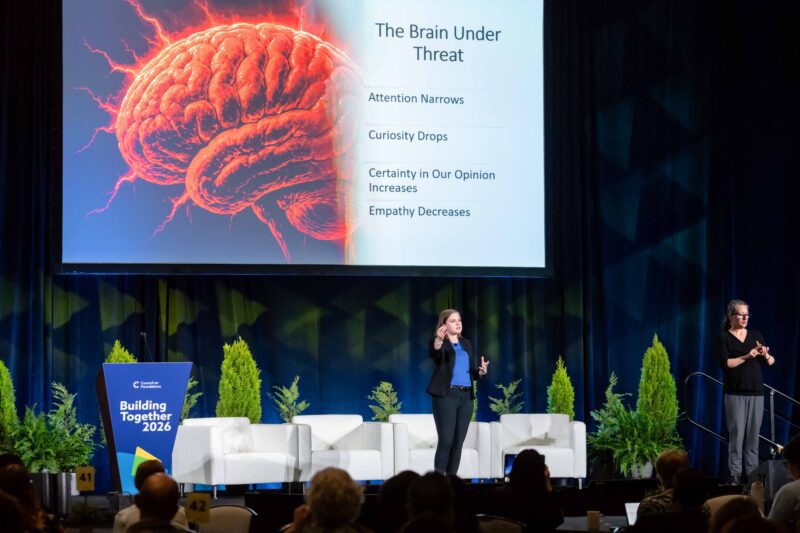 Woman on stage at conference with slide on screen behind her