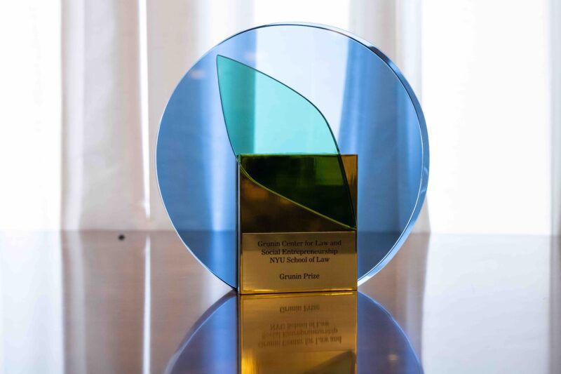 Blue, green, and gold glass Grunin Prize displayed on a reflective table.