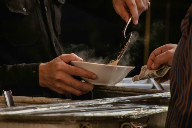 Closeup of hand with soup bowl at table