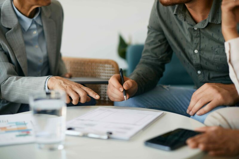 A financial professional and two clients review investment documents during a meeting.