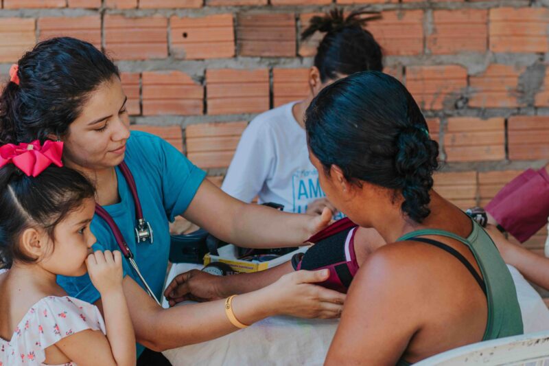 Healthcare worker checks a woman’s blood pressure during a community health screening.