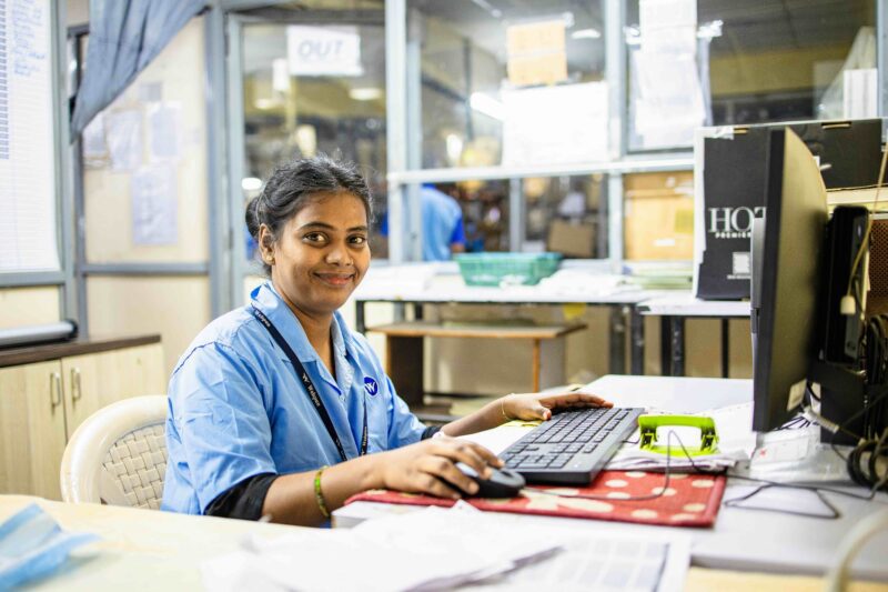 Healthcare worker in India uses a computer workstation in a clinical setting.